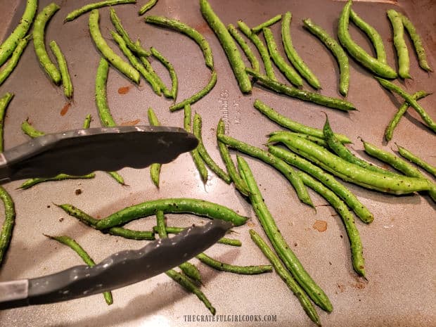 Halfway through baking time, the oven roasted green beans are flipped to other side.