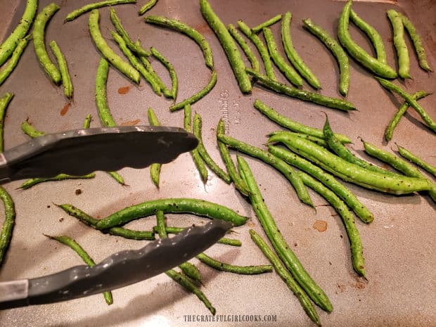 Halfway through baking time, the oven roasted green beans are flipped to other side.