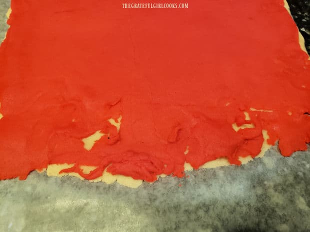 Red dough layer is placed on top of the plain dough rectangle, and holes are patched.