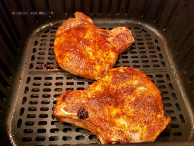 Air fryer pork chops for two have been flipped over to finish cooking.