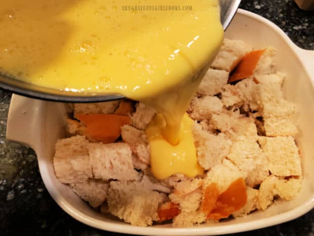 Eggnog mixture is poured over the cubed French bread in the baking dish.