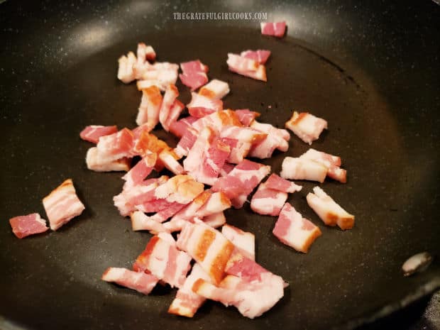 Two slices of bacon are cut in small pieces, then cooked until crispy in skillet.