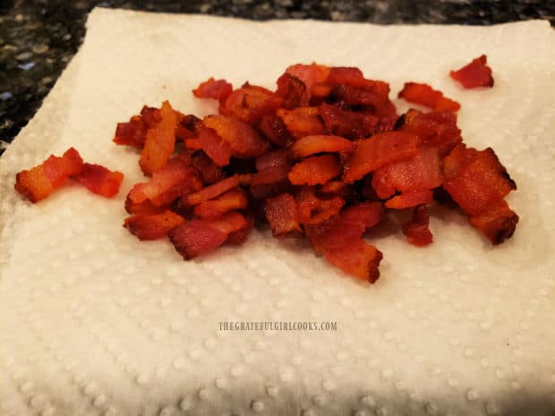 Crisp, browned bacon slices drain on paper towels after being removed from skillet.