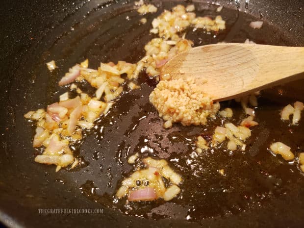 Chopped shallots and minced garlic are cooked in hot oil in skillet.