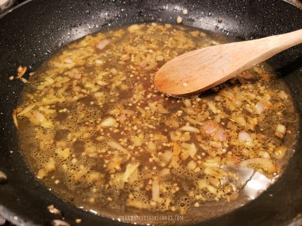 White wine and chicken broth are stirred into the skillet with garlic and shallots.