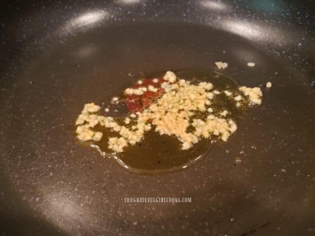 Minced garlic is cooked in olive oil in a large skillet.