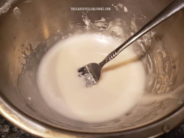 Powdered sugar, vanilla and water are mixed in a bowl to make a sweet glaze for the scones.