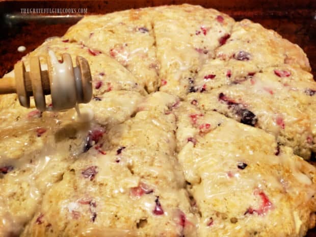 Sweet glaze is drizzled over the baked scones, using a honey spreader.