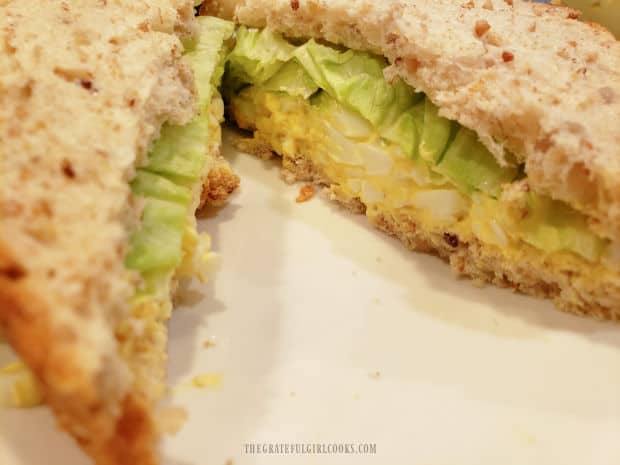 Iceberg lettuce is added to the egg salad for sandwiches and topped with another bread slice.