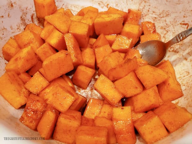 Seasonings, oil and maple syrup are stirred with the butternut squash until coated.