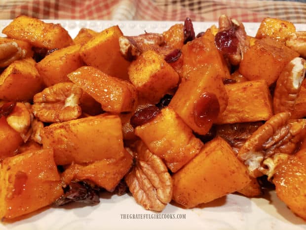 The maple butternut squash with pecans and cranberries is served on a white platter.