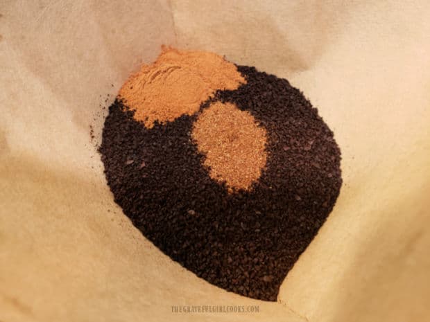 Ground coffee, cinnamon and cloves are placed into a coffee filter before brewing.