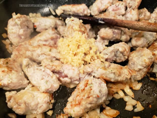 Four minced garlic cloves are added to the pan-seared sausage pieces (or slices).