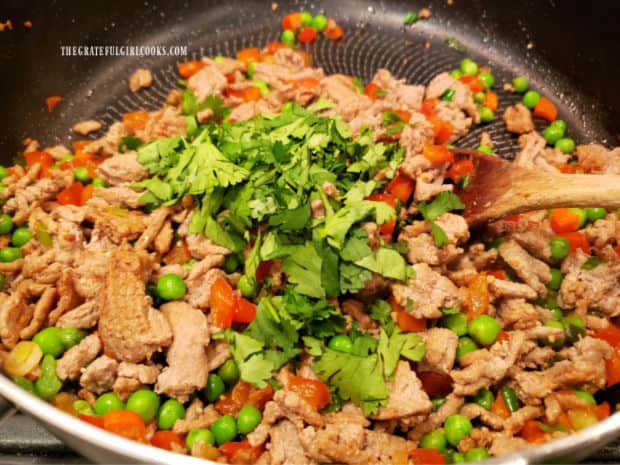 Chopped cilantro is stirred into the stir fry, off of the heat.