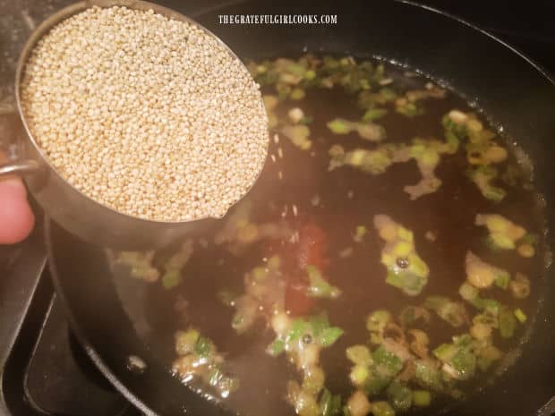A cup of uncooked couscous is added to the boiling liquid in the skillet.