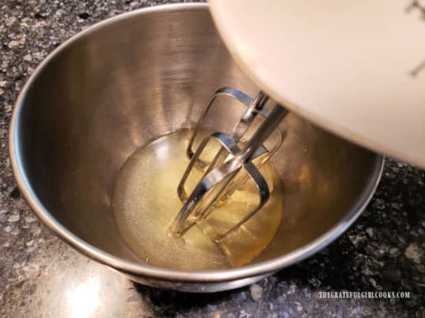 Two egg whites are beaten using an electric mixer.