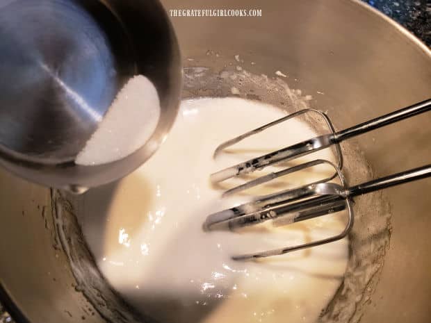 Granulated sugar is added, a little at a time, to the beaten egg white mixture.