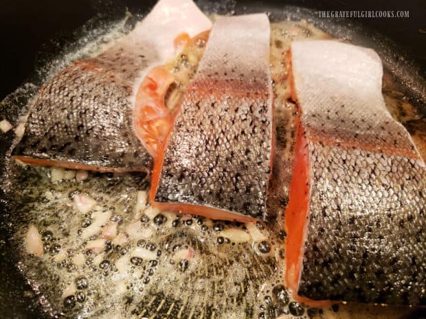 Steelhead fillets are cooked, skin side up, in a skillet with melted butter and shallots.