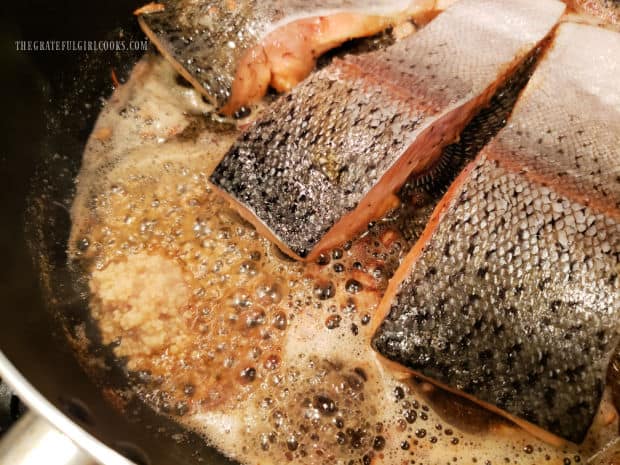 Browned butter with shallots, garlic and herbs are cooked in skillet with 3 steelhead trout fillets.