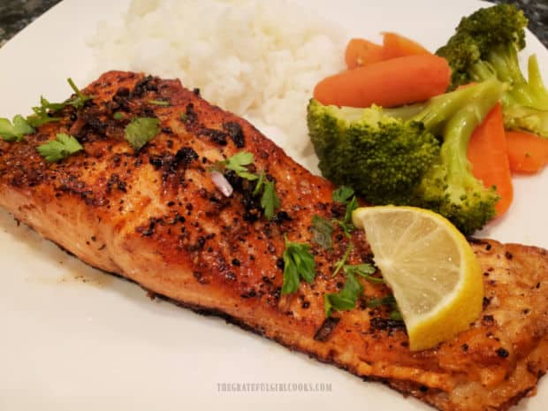 A white plate with pan-seared steelhead trout, broccoli and rice on it.