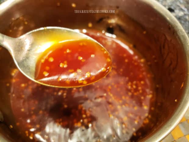 The Asian style sauce thickens as it cooks and is shown on a spoon.