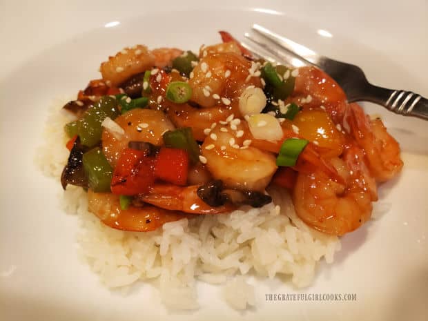 Teriyaki shrimp bowl is served on rice, with green onion/sesame seed garnish.