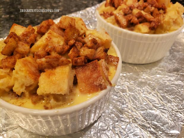 White ramekins are very full of bread cubes, apple/pecan mixture and egg filling.