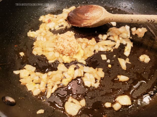 Minced garlic and ginger are added to the softened and lightly browned onions.