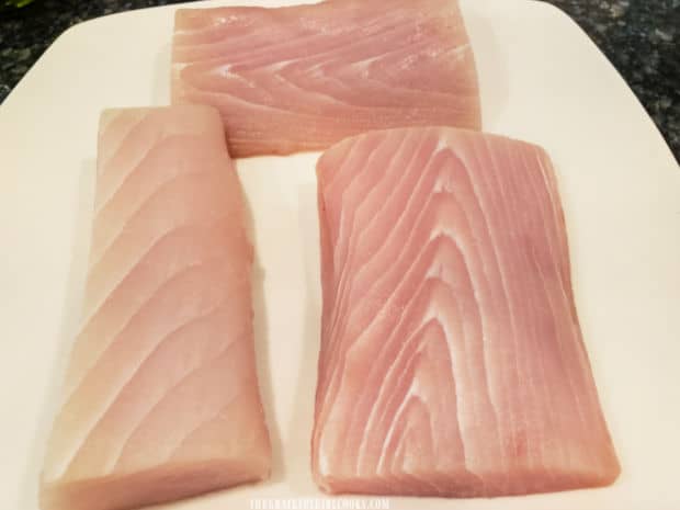 Three boneless mahi mahi fillets are patted dry, then rest on plate before seasoning.