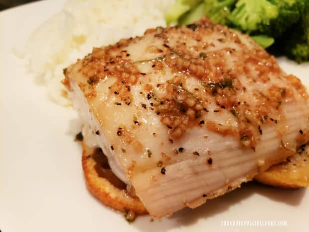 The easy baked mahi mahi fillet is served on top of lemon slices, on a white plate.