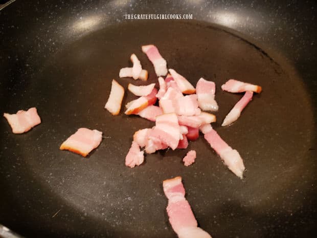A slice of bacon is cut into small pieces, then is cooked in a skillet until crispy.