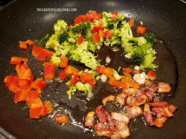 Chopped red bell pepper, broccoli and green onion are added to cooked bacon in the skillet.