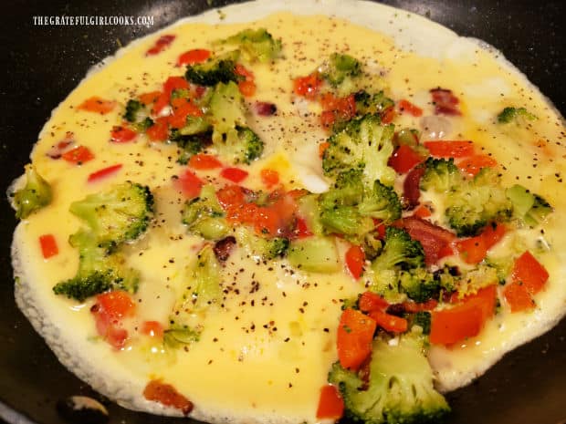 Beaten eggs, salt and pepper are added to the veggies and bacon in the skillet.