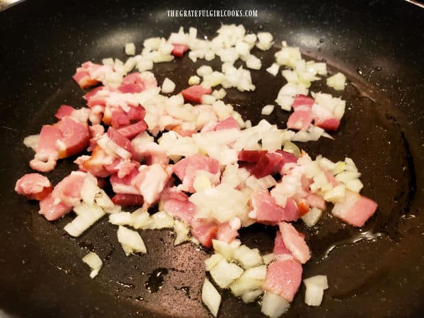 Chopped onions and small pieces of bacon, cooking in a skillet.