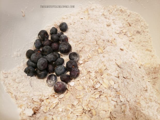 Blueberries are added to the bowl containing the muffin's dry ingredients.