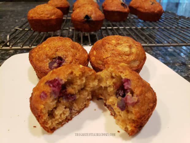 Muffins on a white plate, with rack of muffins in the background.