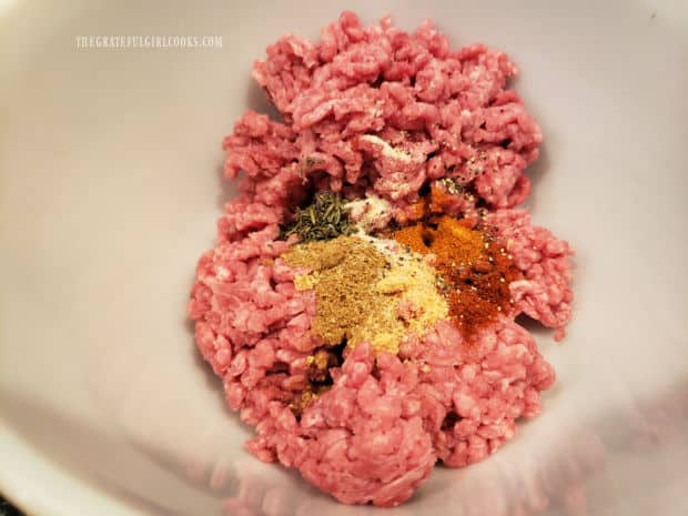 Spices are added to a half pound of ground beef in a bowl, and mixed, to combine.