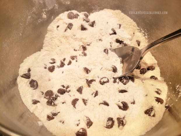 Flour, sugar, baking powder, salt, cinnamon, baking soda and chocolate chips are combined in a bowl.