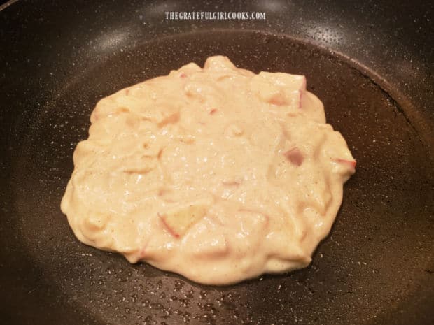 One of the chunky apple cinnamon pancakes cooking in a skillet.