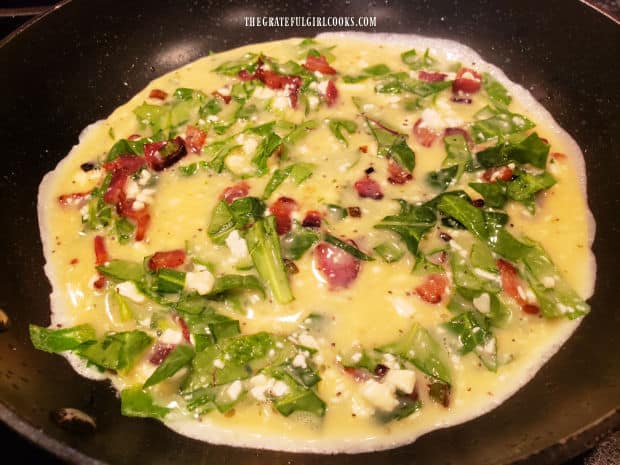 Mixture for the Florentine eggs and bacon is poured into a large skillet to cook.