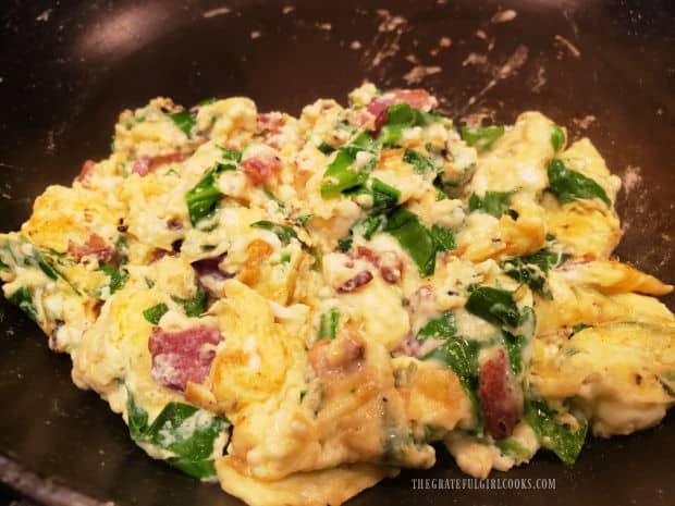 Florentine eggs and bacon is scrambled in a large skillet.