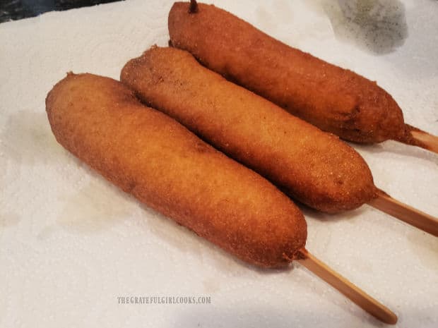 Cooked homemade corn dogs drain on paper towels after cooking.