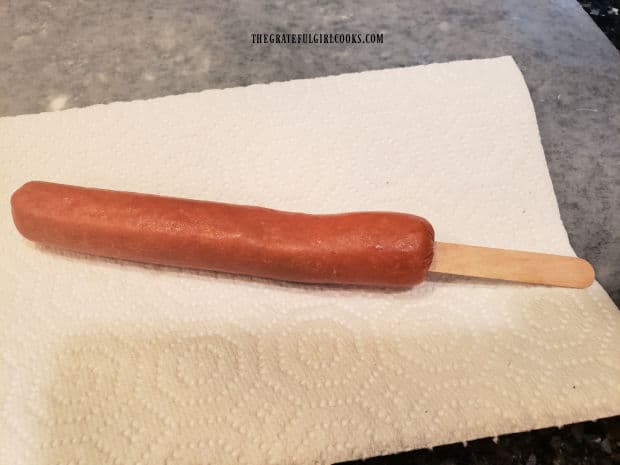 Stick is inserted into hot dog, then it is patted dry.