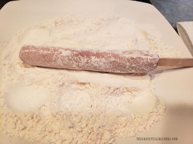 Hot dog is rolled in flour before dipping it in batter.