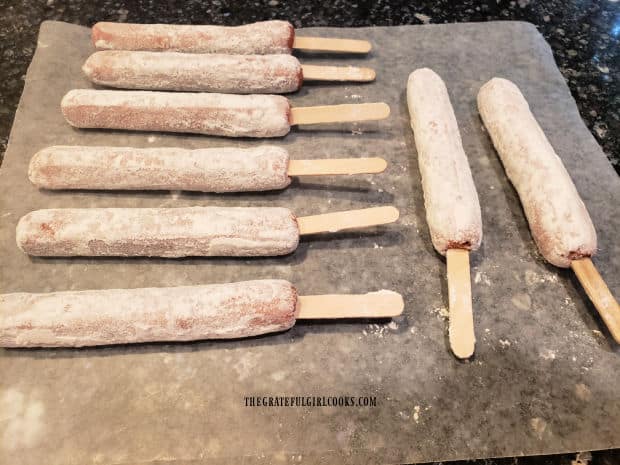 Hot dogs are coated with flour, and are ready to be battered and fried.