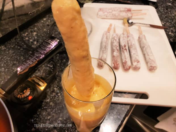 Batter is put in tall glass, then hot dog is dipped in batter, to cover.