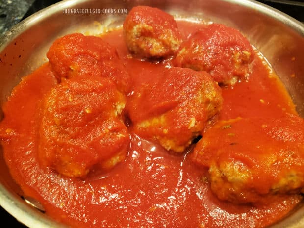 Cooked meatballs are heated back up in a skillet of Italian-seasoned marinara sauce.