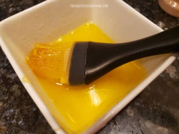 Butter is melted and garlic powder is added before brushing it on rolls.