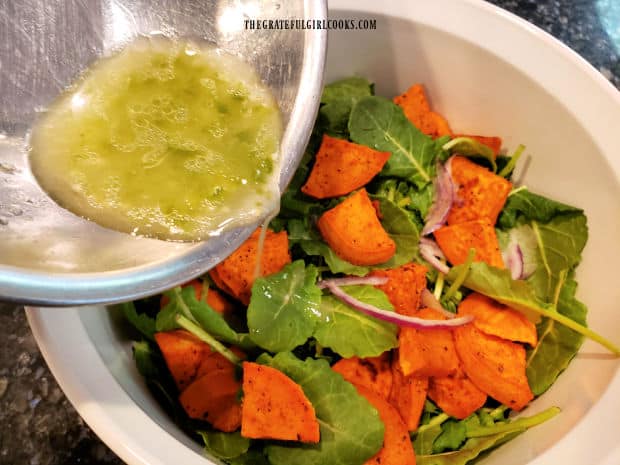 Lime salad dressing is drizzled over the top of the kale and sweet potato salad.
