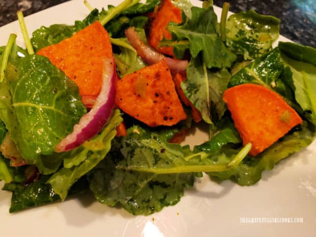 Kale and sweet potato salad is tossed to combine ingredients, then served as side dish.
